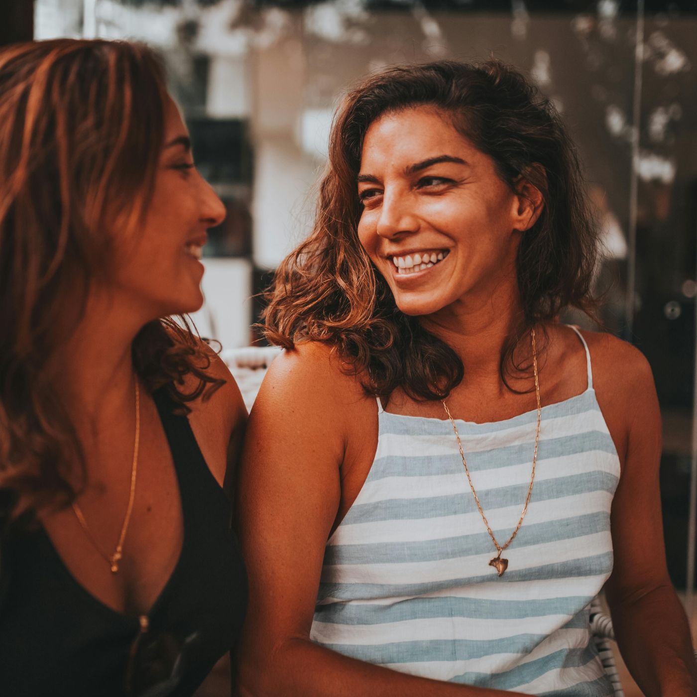 Two friends chatting at an outdoor café in Beech Grove, highlighting easy, genuine conversations that grow friendships after 40.