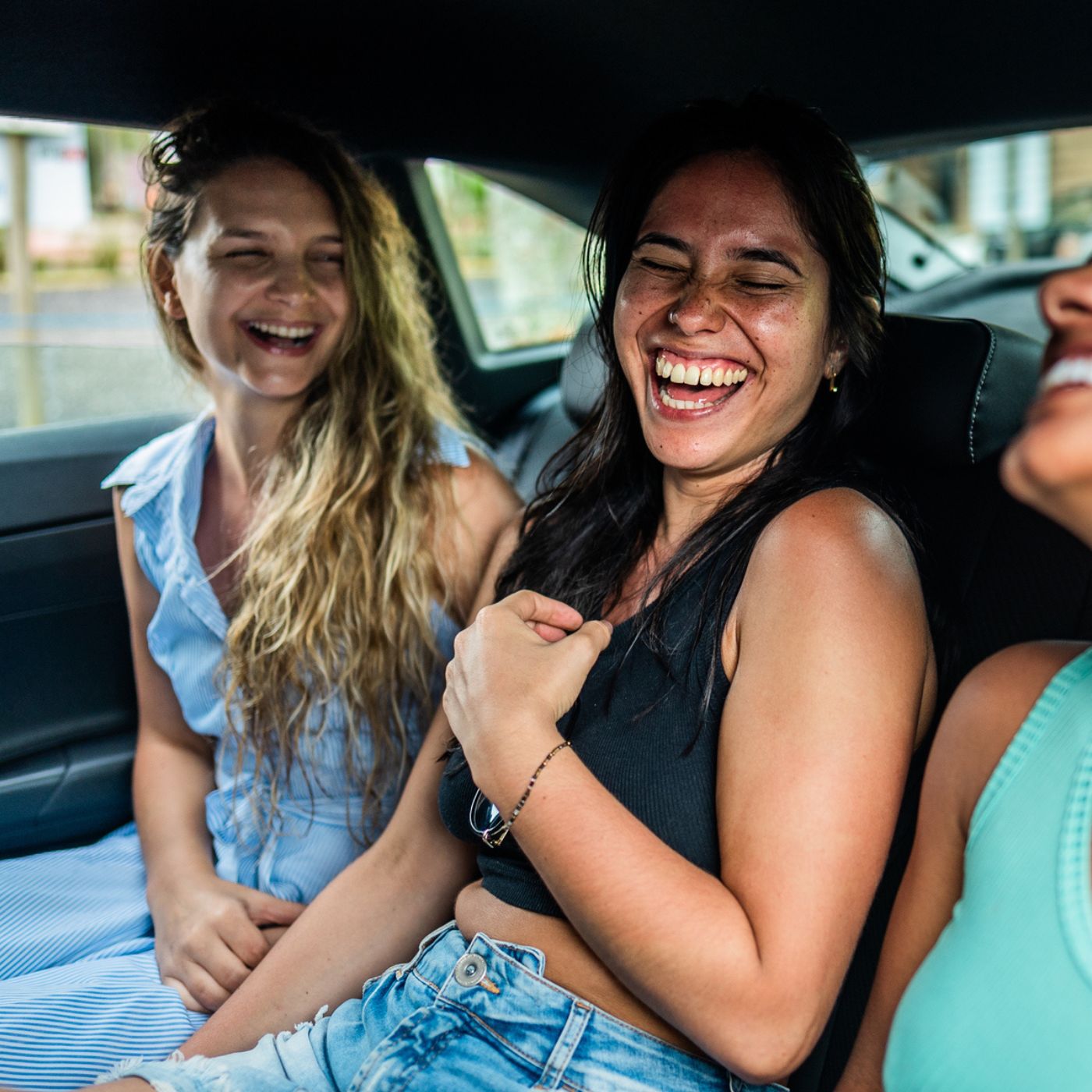 Three women laughing happily together in a car in West Riverfront neighborhood