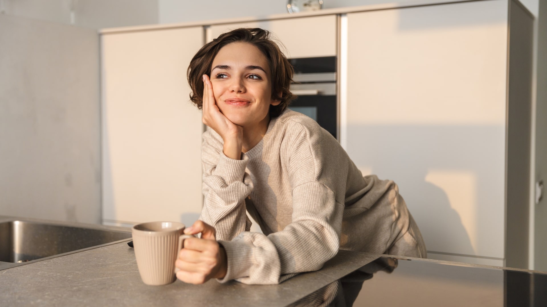 Woman in a cozy sweater smiling with a coffee mug in her new home, reflecting the feeling of being new in town.