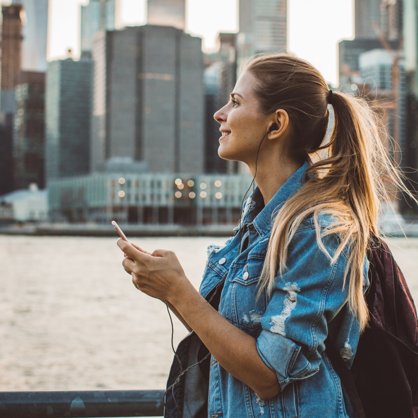 Woman outdoors by Walton waterfront with city skyline, looking up with curiosity