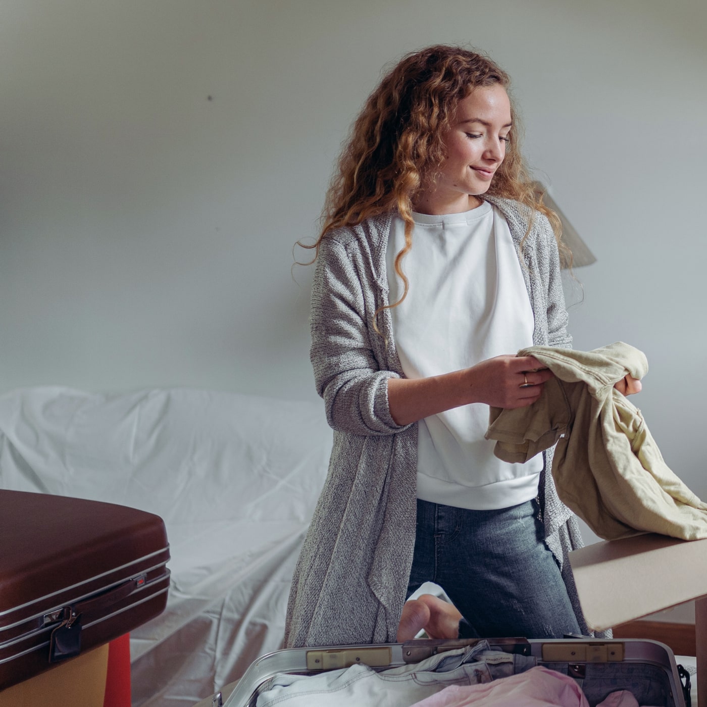 Young woman unpacking suitcase in cozy Fort Hamilton apartment, settling into new home