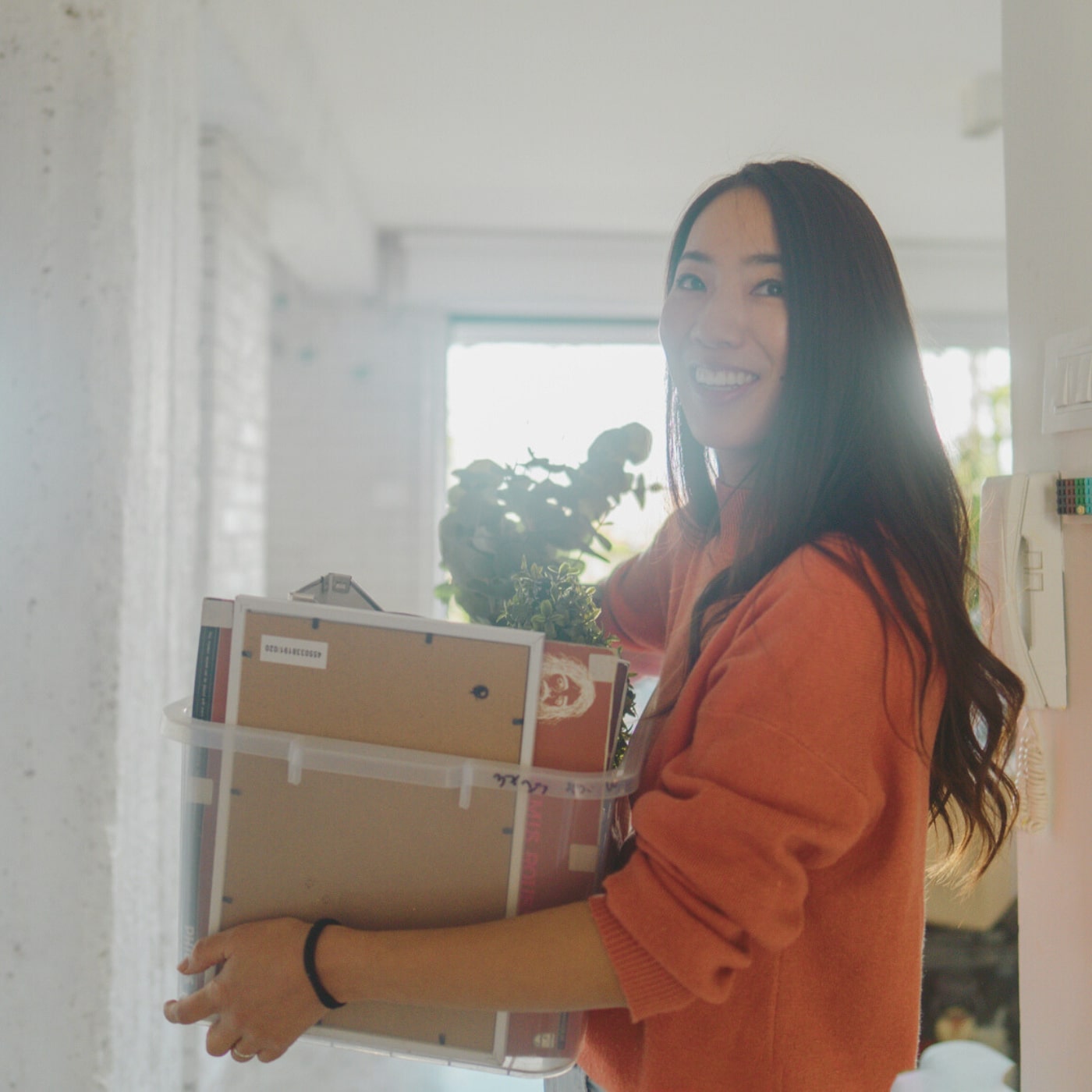 Smiling woman carrying box moving into new apartment in Pomona neighborhood