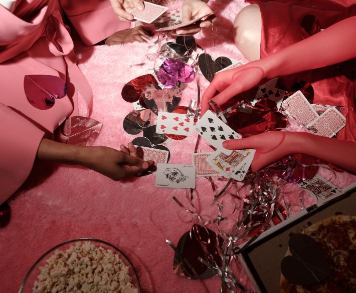 Group of female friends playing cards at a party, surrounded by popcorn and decorations – symbolizing friendship and shared moments