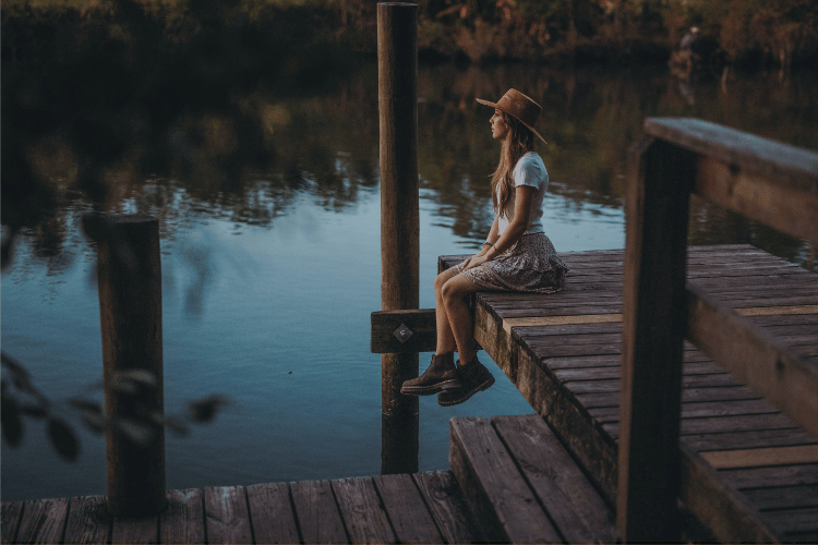 A woman sitting peacefully on a dock at sunset, symbolizing calm connection and the emotional essence of Gofrendly