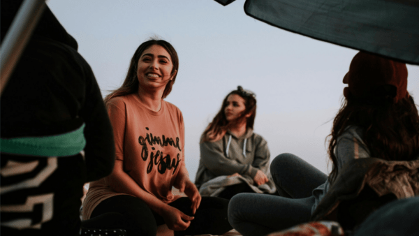 A young woman smiling and connecting with new friends outdoors, symbolizing the excitement of finding new friends.