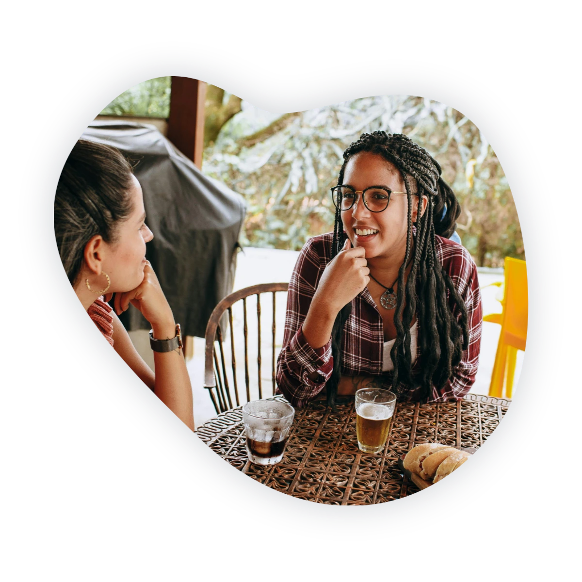 How to make friends as an adult: two women talking over drinks at an outdoor table.
