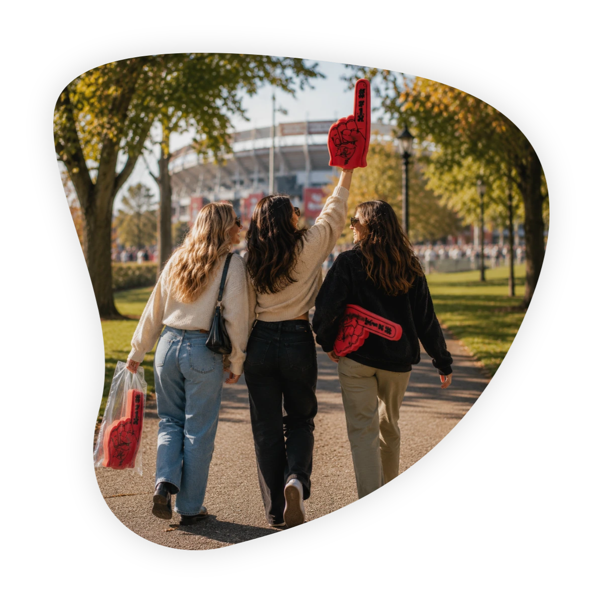 Make friends during football season: three women walking toward a stadium with red foam fingers.