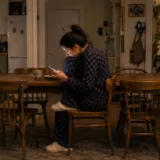 Should you ghost a friend? Woman looking at her phone alone at the kitchen table